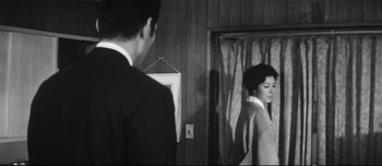 Movie still from “When a Woman Ascends the Stairs” (1960), directed by Mikio Naruse – A man and a woman standing in front of a mirror; Medium shot, Over the shoulder angle