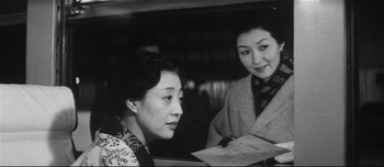 Movie still from “When a Woman Ascends the Stairs” (1960), directed by Mikio Naruse – Two women are sitting at a table and one is holding a piece of paper; Medium shot, Low angle