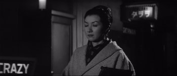 Movie still from “When a Woman Ascends the Stairs” (1960), directed by Mikio Naruse – A woman in a black and white photo looking at the camera; Close Up shot, Low angle