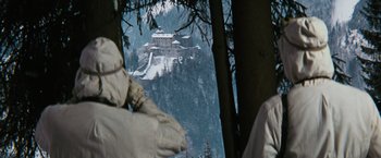 Movie still from “Where Eagles Dare” (1968), directed by Brian G. Hutton – A view of a castle in the middle of a snowy forest; Wide shot, Low angle