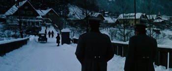 Movie still from “Where Eagles Dare” (1968), directed by Brian G. Hutton – A man in a black coat and hat standing in the snow; Wide shot, Low angle