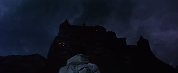 Movie still from “Where Eagles Dare” (1968), directed by Brian G. Hutton – A person standing in front of a castle at night; Extreme Wide shot, Low angle