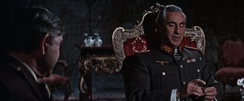 Movie still from “Where Eagles Dare” (1968), directed by Brian G. Hutton – A man sitting in a chair wearing a suit and tie; Medium shot, Low angle