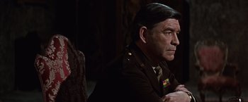 Movie still from “Where Eagles Dare” (1968), directed by Brian G. Hutton – A man in a military uniform sitting in front of a chair; Close Up shot, Over the shoulder angle