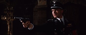 Movie still from “Where Eagles Dare” (1968), directed by Brian G. Hutton – A man in a uniform holding a gun in the dark; Medium shot, Low angle