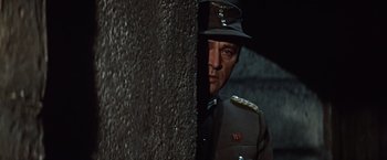 Movie still from “Where Eagles Dare” (1968), directed by Brian G. Hutton – A man in a military uniform standing next to a wall; Close Up shot, Low angle