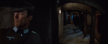 Movie still from “Where Eagles Dare” (1968), directed by Brian G. Hutton – A man standing in a dark room next to a wall; Close Up shot, Over the shoulder angle