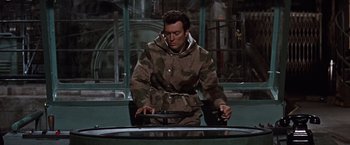 Movie still from “Where Eagles Dare” (1968), directed by Brian G. Hutton – A man wearing a coat and sitting in a car; Medium shot, High angle