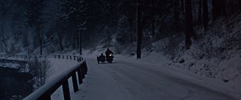Movie still from “Where Eagles Dare” (1968), directed by Brian G. Hutton – A man riding a motorcycle down a snow covered road; Extreme Wide shot, High angle