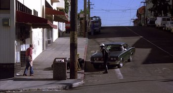 Movie still from “Where the Buffalo Roam” (1980), directed by Art Linson – A man standing on the side of the road next to a parked car; Wide shot, High angle