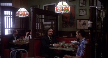 Movie still from “Where the Buffalo Roam” (1980), directed by Art Linson – Two men are sitting at a booth in a restaurant; Wide shot, Over the shoulder angle