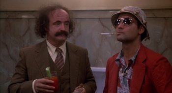 Movie still from “Where the Buffalo Roam” (1980), directed by Art Linson – Two men standing next to each other in a bathroom; Medium shot, Low angle