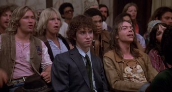 Movie still from “Where the Buffalo Roam” (1980), directed by Art Linson – A group of people sitting in front of each other in a room; Medium shot, Low angle