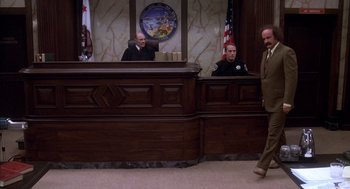 Movie still from “Where the Buffalo Roam” (1980), directed by Art Linson – A man walking in front of a judge in a courtroom; Wide shot, High angle