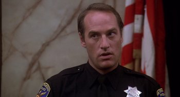 Movie still from “Where the Buffalo Roam” (1980), directed by Art Linson – A police officer in uniform looking to his left; Close Up shot, Low angle