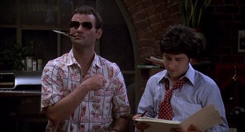 Movie still from “Where the Buffalo Roam” (1980), directed by Art Linson – A man smoking a cigarette next to another man wearing a tie; Medium shot, Low angle