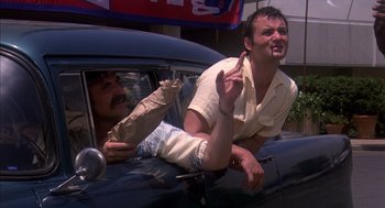 Movie still from “Where the Buffalo Roam” (1980), directed by Art Linson – Two men in the back seat of a car; Medium shot, Low angle