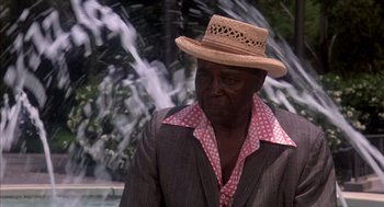 Movie still from “Where the Buffalo Roam” (1980), directed by Art Linson – An older man wearing a straw hat in front of a waterfall; Close Up shot, Low angle