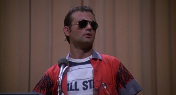 Movie still from “Where the Buffalo Roam” (1980), directed by Art Linson – A man wearing sunglasses standing in front of a microphone; Close Up shot, Low angle