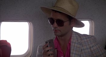 Movie still from “Where the Buffalo Roam” (1980), directed by Art Linson – A man wearing a hat and sunglasses is holding a cell phone; Close Up shot, Low angle