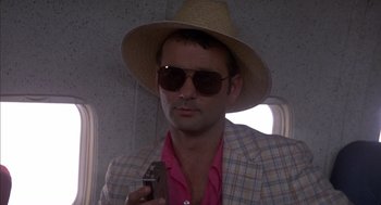 Movie still from “Where the Buffalo Roam” (1980), directed by Art Linson – A man wearing a hat and sunglasses holding a cell phone; Close Up shot, Low angle
