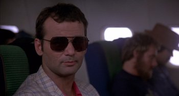 Movie still from “Where the Buffalo Roam” (1980), directed by Art Linson – A man wearing sunglasses and a plaid shirt; Close Up shot, Low angle