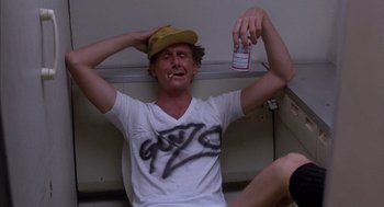 Movie still from “Where the Buffalo Roam” (1980), directed by Art Linson – A man in a yellow hat holding a bottle of alcohol; Medium shot, Low angle