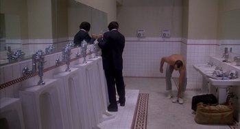 Movie still from “Where the Buffalo Roam” (1980), directed by Art Linson – A man in a black suit is standing in front of a mirror; Wide shot, High angle