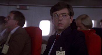Movie still from “Where the Buffalo Roam” (1980), directed by Art Linson – A man in a suit and tie sitting on a plane; Close Up shot, Over the shoulder angle