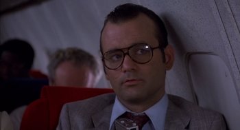 Movie still from “Where the Buffalo Roam” (1980), directed by Art Linson – A man in a suit and tie sitting in a chair; Close Up shot, Low angle