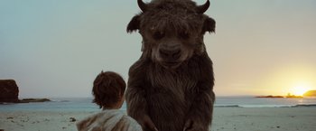 Movie still from “Where the Wild Things Are” (2009), directed by Spike Jonze – A person standing next to an animal on a beach; Medium shot, Over the shoulder angle