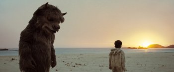 Movie still from “Where the Wild Things Are” (2009), directed by Spike Jonze – A person and a yak on the beach; Wide shot, Over the shoulder angle