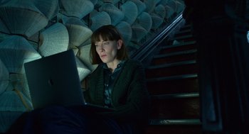 Movie still from “Where'd You Go, Bernadette” (2019), directed by Richard Linklater – A woman sitting on the stairs using a laptop computer; Medium shot, Low angle