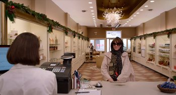 Movie still from “Where'd You Go, Bernadette” (2019), directed by Richard Linklater – A woman standing at a counter in a store; Medium shot, Low angle