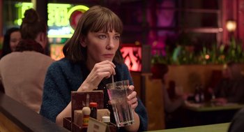 Movie still from “Where'd You Go, Bernadette” (2019), directed by Richard Linklater – A woman sitting at a table with a drink in front of her; Close Up shot, Over the shoulder angle