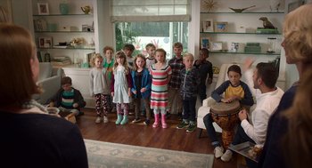 Movie still from “Where'd You Go, Bernadette” (2019), directed by Richard Linklater – A group of children standing in front of a living room; Wide shot, High angle