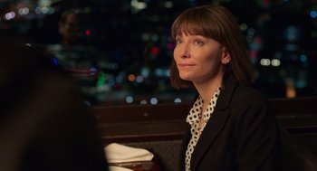 Movie still from “Where'd You Go, Bernadette” (2019), directed by Richard Linklater – A woman sitting at a table in front of a city skyline; Close Up shot, Over the shoulder angle