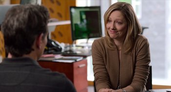 Movie still from “Where'd You Go, Bernadette” (2019), directed by Richard Linklater – A woman sitting in front of a man in front of a computer; Medium shot, Over the shoulder angle