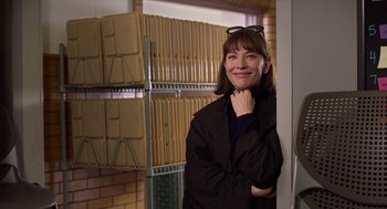 Movie still from “Where'd You Go, Bernadette” (2019), directed by Richard Linklater – A woman standing in front of a wall of file folders; Medium shot, Over the shoulder angle