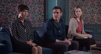 Movie still from “Where'd You Go, Bernadette” (2019), directed by Richard Linklater – A group of three people sitting on a couch; Medium shot, Over the shoulder angle