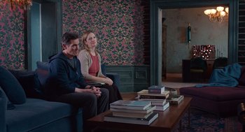 Movie still from “Where'd You Go, Bernadette” (2019), directed by Richard Linklater – A man and a woman sitting on a couch in a living room; Wide shot, Over the shoulder angle
