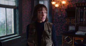 Movie still from “Where'd You Go, Bernadette” (2019), directed by Richard Linklater – A woman standing in a room with a wall in the background; Medium shot, Over the shoulder angle