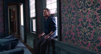 Movie still from “Where'd You Go, Bernadette” (2019), directed by Richard Linklater – A man sitting on top of a window sill; Wide shot, High angle