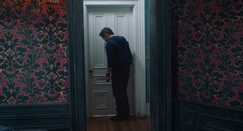 Movie still from “Where'd You Go, Bernadette” (2019), directed by Richard Linklater – A man standing in front of an open door; Wide shot, High angle