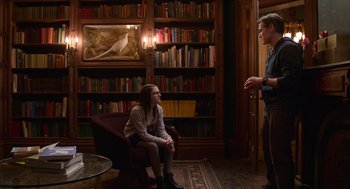 Movie still from “Where'd You Go, Bernadette” (2019), directed by Richard Linklater – A man and a woman are sitting in front of a book case; Wide shot, Over the shoulder angle
