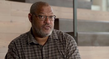 Movie still from “Where'd You Go, Bernadette” (2019), directed by Richard Linklater – An older man wearing glasses and a checkered shirt; Close Up shot, Low angle