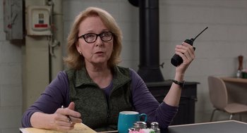 Movie still from “Where'd You Go, Bernadette” (2019), directed by Richard Linklater – A woman sitting at a table holding a camera; Close Up shot, Over the shoulder angle