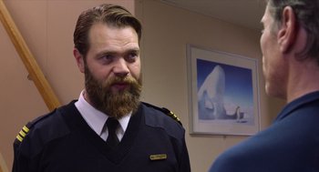 Movie still from “Where'd You Go, Bernadette” (2019), directed by Richard Linklater – A man with a long beard and mustache wearing a uniform; Medium shot, Over the shoulder angle