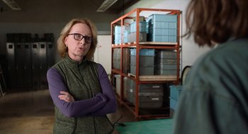 Movie still from “Where'd You Go, Bernadette” (2019), directed by Richard Linklater – A woman standing in front of a rack of boxes; Close Up shot, Over the shoulder angle