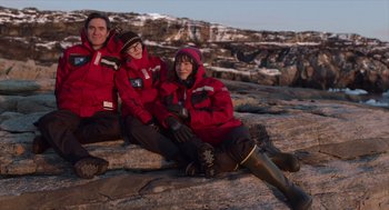 Movie still from “Where'd You Go, Bernadette” (2019), directed by Richard Linklater – Three people sitting on the rocks wearing red jackets; Wide shot, High angle